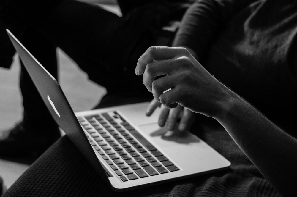 A black and white photo of a person using a laptop as they would during an online DBT program session